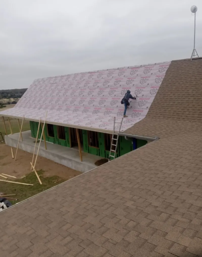 Worker preparing underlayment for a metal roof installation in Maize